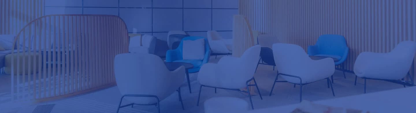 A man walking towards a glass building while carrying a bag.